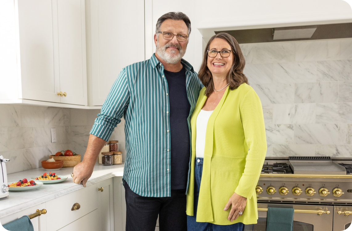 older man, woman smilingin kitchen with waffles