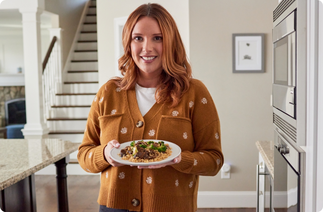 woman holding meal in kitchen